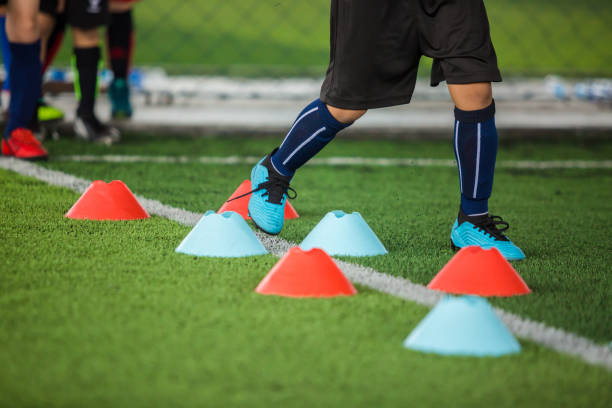 istock Kid soccer players jogging between marker cones on green artificial turf for training. 1175248734