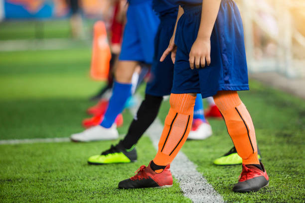 istock Kid soccer players standing over white line on green artificial turf ready to training and start game. 1175248793