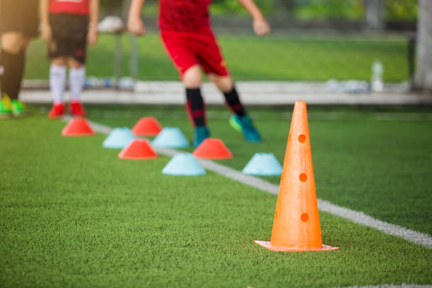 istock Orange marker cones on green artificial turf with blurry kid soccer player jogging between marker cones for training. Soccer training equipment. 1175248850