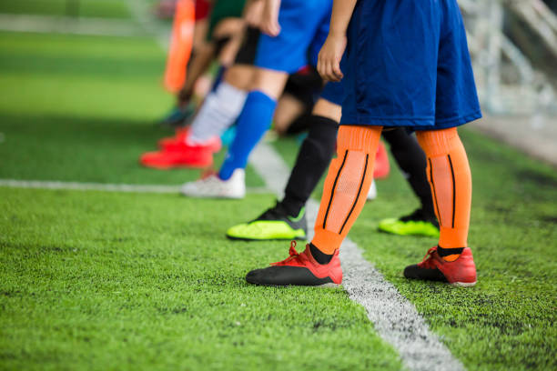istock Kid soccer players standing over white line on green artificial turf ready to training and start game. 1175248907