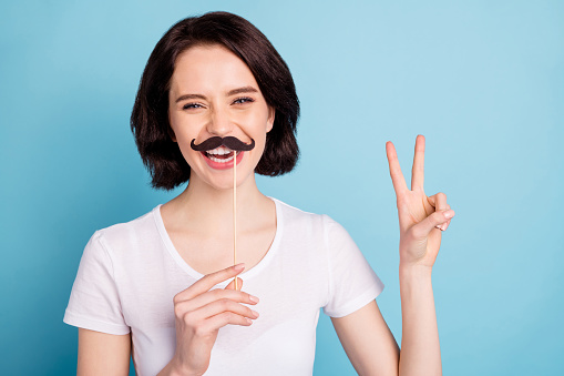 Close-up portrait of her she nice attractive lovely glad cheerful cheery girl showing fake mustache v-sign having, fun isolated on bright vivid shine vibrant blue turquoise color background