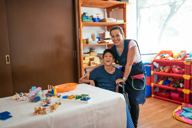 lavorare in asilo nido con bambini con difficoltà di apprendimento - ragazzo in sedia a rotelle con celebral palsy - alternative health care foto e immagini stock