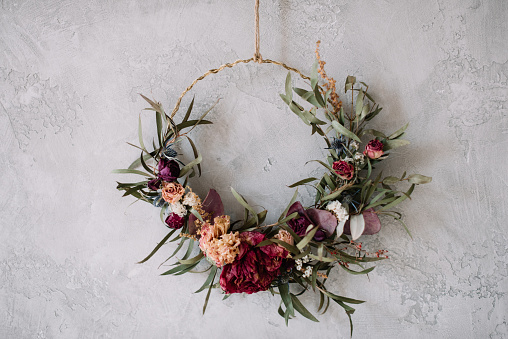 Hermosa corona seca hecha a mano eterna hecha de rosas, flores de hortensia y eucalipto en el fondo gris de la pared photo