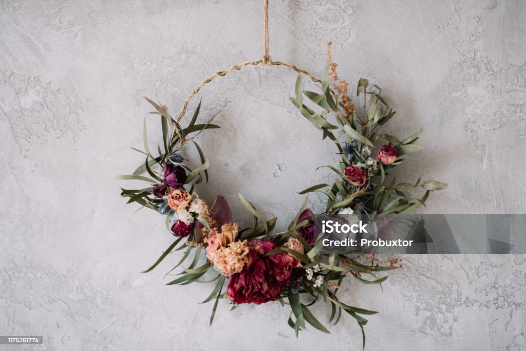 Beautiful hand made everlasting dry wreath made of roses, hydrangea flowers and eucalyptus on the grey wall background Flower Stock Photo