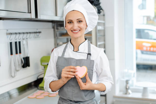 Pastry chef in love with her trade showing it with heart shaped sweets stock photo