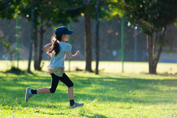 девушка, бегущая в парке - healthy lifestyle nature sports shoe childhood стоковые фото и изображения