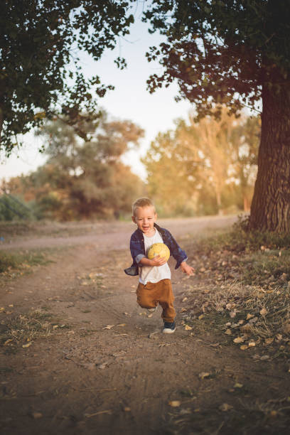 istock Happy little boy is running and holding ball while enjoying his freedom 1175254664
