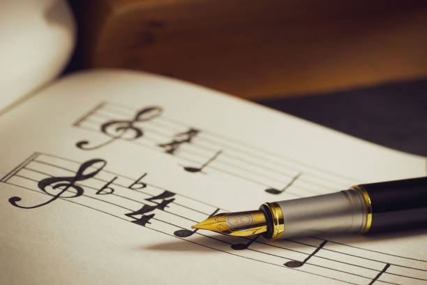 istock Music notes and old book on wooden table background in morning light. 1175260706
