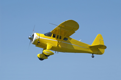 Yellow airplane in flight. Howard Aircraft DGA-15P. Built in 1943.