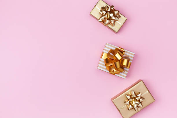 istock Festive composition for birthday, christmas or weddGolden gift or present boxes on pink background top view. Festive composition for birthday, christmas or wedding. Flat lay. 1175262701
