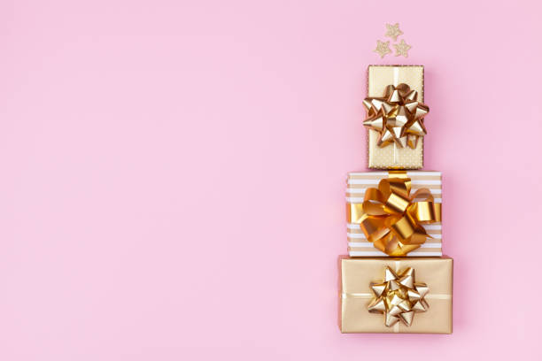 istock Stack of golden gift or present boxes in the form of Christmas tree on pink background top view. Celebration Christmas or New year concept. Flat lay. 1175262720
