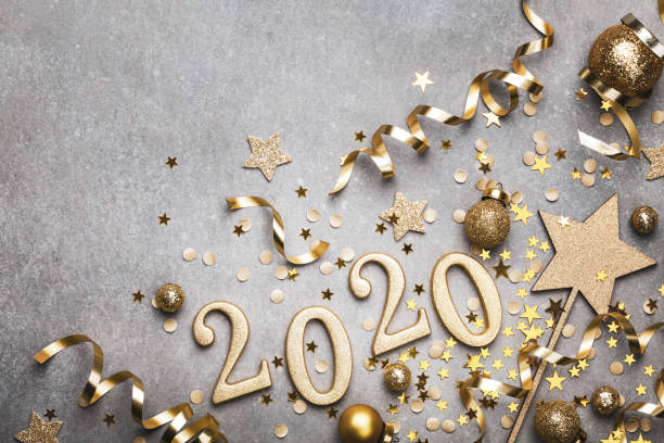 Holiday background with golden Christmas decorations and New year 2020 numbers and confetti stars top view. Holiday background with golden Christmas decorations and New year 2020 numbers and confetti stars top view with copy space. 2020 stock pictures, royalty-free photos & images