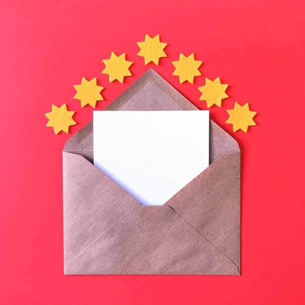 istock Blank postcard with brown craft paper envelope on red background, composition with sunny yellow felt stars for stationery mock ups, postcards, letters, greeting cards, prints, invitations, flyers. 1175262927