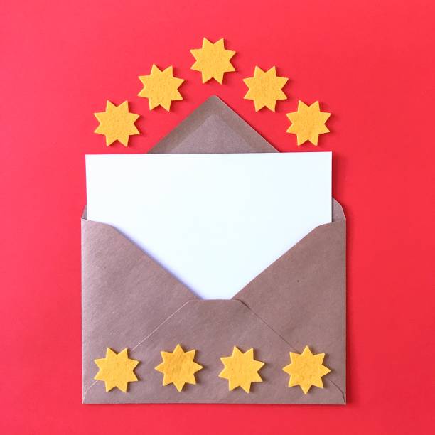 istock Blank postcard with brown craft paper envelope on red background, composition with sunny yellow felt stars for stationery mock ups, postcards, letters, greeting cards, prints, invitations, flyers. 1175262928