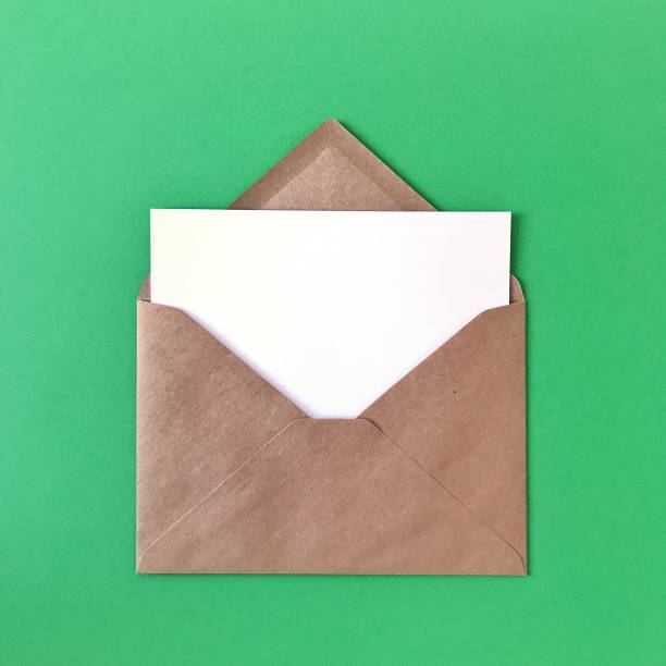 istock Green postcard in brown craft paper envelope on green background. Mock up flat lay for greeting cards, postcards, prints, stationery, invitations, letters, paper. 1175263018