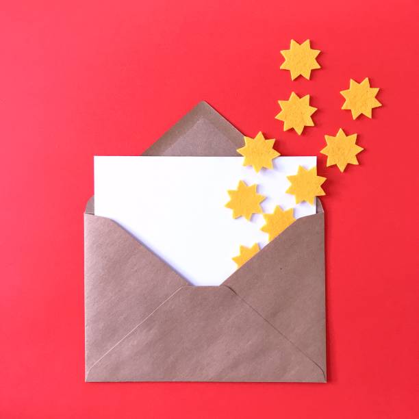 istock Blank postcard with brown craft paper envelope on red background, composition with sunny yellow felt stars for stationery mock ups, postcards, letters, greeting cards, prints, invitations, flyers. 1175263033