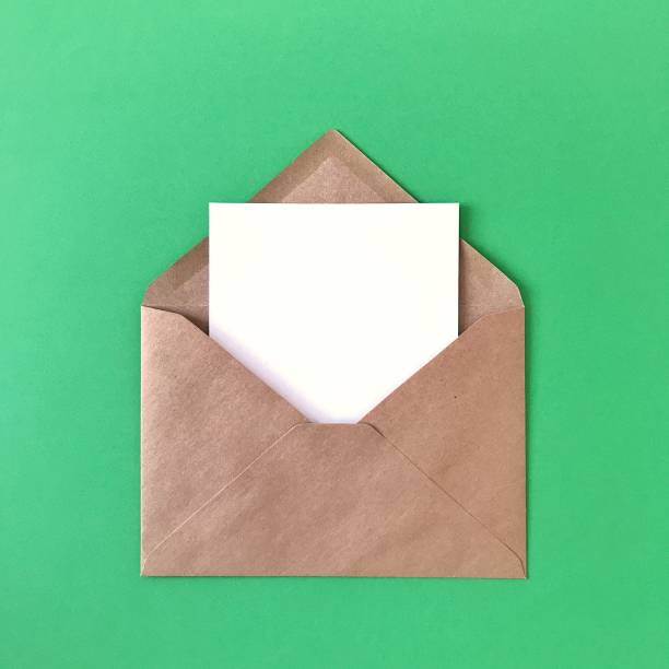 istock Green postcard in brown craft paper envelope on green background. Mock up flat lay for greeting cards, postcards, prints, stationery, invitations, letters, paper. 1175263056