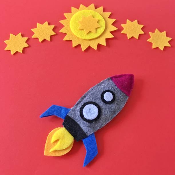 istock Colorful handmade rocket ship crafted with felt fabric. Yellow stars on red background with rocketship toy to DIY. Crafting supplies for hand made baby crib mobile for nursery. Happy colorful image. 1175263141