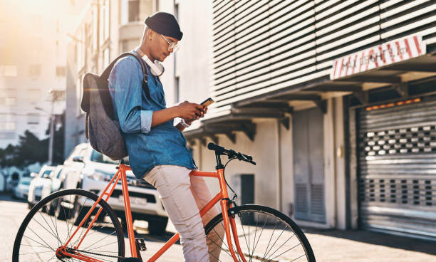 Technology makes life so much easier Shot of a young man using his cellphone while standing outside with his bicycle hipster bike stock pictures, royalty-free photos & images