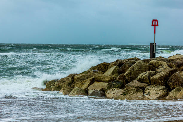 istock Crashing waves on a stony groyne (breakwater) during a massive storm under a grey sky 1175266978