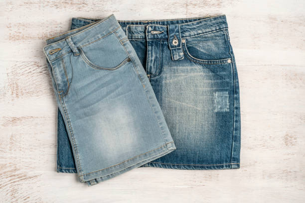 jupes de jean sur un fond en bois avec l'espace de copie - skirt consumerism jeans pants photos et images de collection