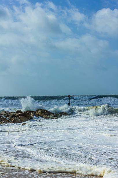 istock Crashing waves on a stony groyne (breakwater) during a massive storm under a majestic blue sky and white clouds 1175268330