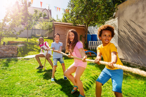 istock Group of kids play pulling rope game on the lawn 1175269683