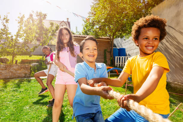 istock Group of kids play pulling rope game on playground 1175269689