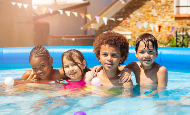 istock Four kids play in backyard swimming pool together 1175269796