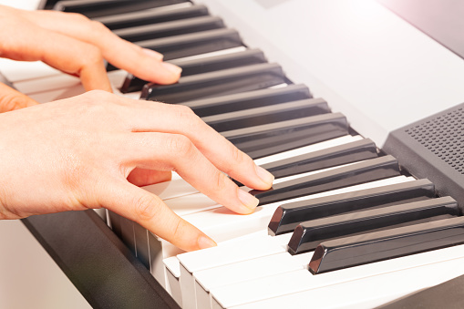 Close-up picture of woman's hand playing digital piano