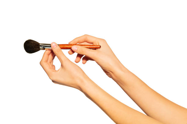 Close up picture of woman's hands holding makeup powder brush isolated on white background