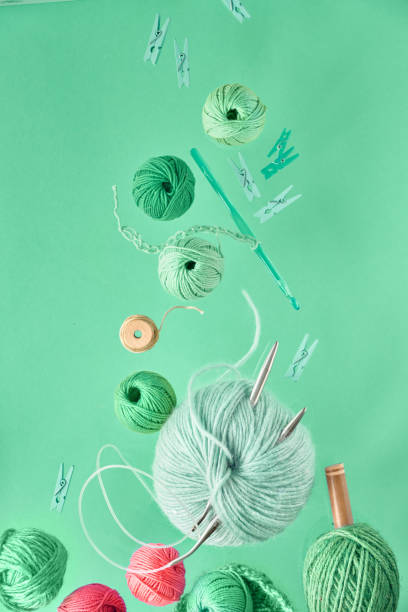 Various wool yarn and knitting needles, creative knitting hobby background on neo mint background