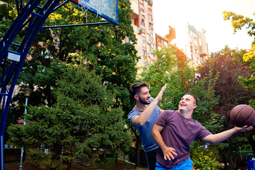 Young man with down syndrome playing basketball with friends