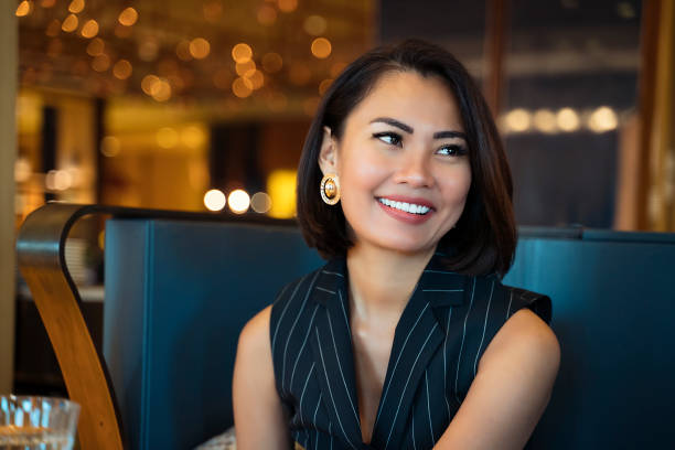 verticale d'une femme d'affaires asiatique souriant à l'appareil-photo dans le bureau - high society photos et images de collection