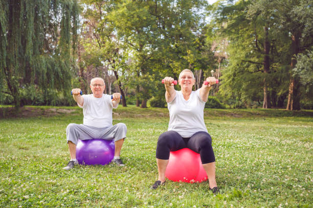 istock together we workout better - Smiling senior couple practice with dumbbells 1175280951