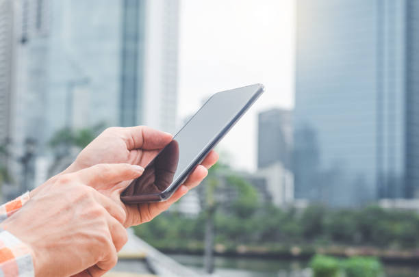 istock close up handsome man using hand typing smartphones and touch screen working search with app devices outdoor in city with sunrise and building background. 5G technology connecting the world. 1175281619