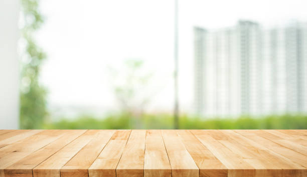 istock Real wood table top texture on blur leaf tree garden and wall building from city,park 1175284533