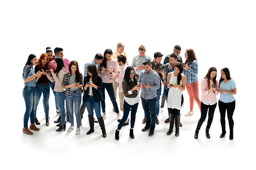 Happy group of people looking at social media on their cell phones at the studio and smiling - isolated over a white background