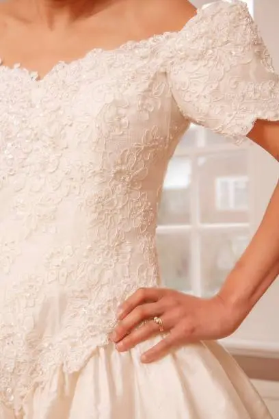 Closeup of an Indian Asian woman wearing a vintage ivory wedding dress with lace detail