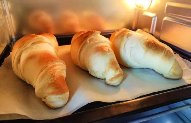 Croissants are cooked in the oven. Baking for breakfast. Homemade desserts. Golden crust.