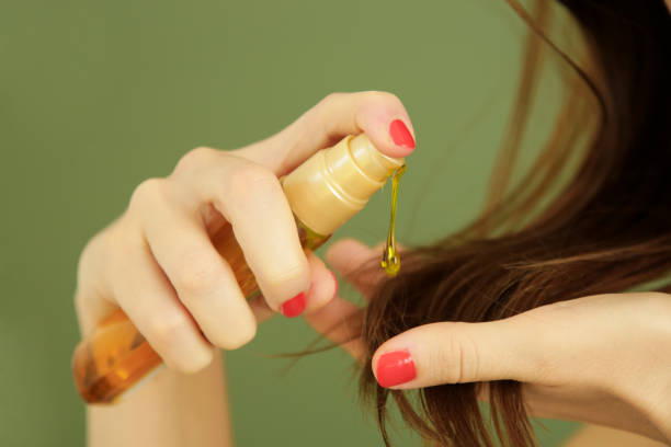 mujer aplicando aceite en las puntas del cabello, puntas de pelo dividido, cabello seco o concepto de protección solar - wellness products fotografías e imágenes de stock