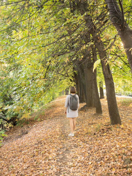 istock Woman walking alone in park during autumn sunny day 1175295453