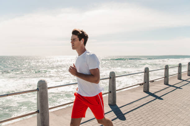 istock Young Man Jogging On Promenade At Beach 1175297342