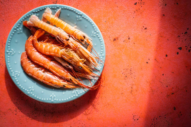 Raw srimps in a blue dish on coral color