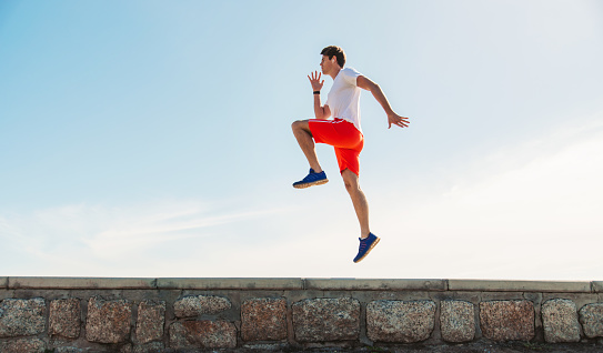 Young man exercising by the sea, skipping in the spot.