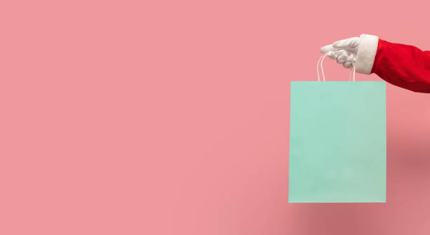 santa claus trzyma niebieską torbę na zakupy na odizolowanym różowym tle. - christmas bag shopping bag gift zdjęcia i obrazy z banku zdjęć