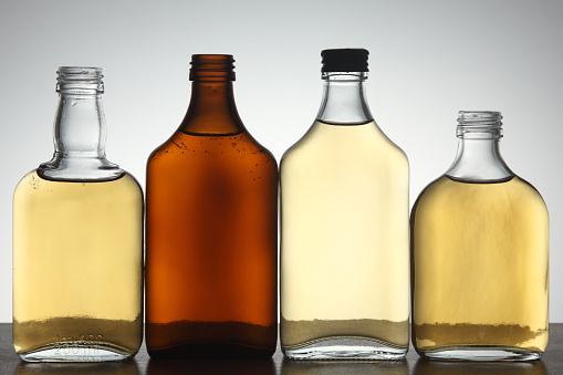 Front view of four backlit glass bottles full of liquid