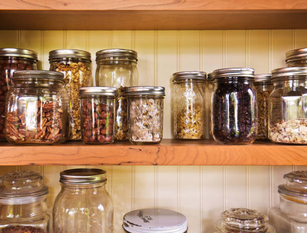 Pantry or kitchen shelf with assorted dried food ingredients in a variety of different glass storage jars in a close up full frame view