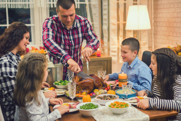 młody ojciec rzeźbienia tradycyjnych wypchane dziękczynienia indyka - roast turkey turkey cutting roasted zdjęcia i obrazy z banku zdjęć