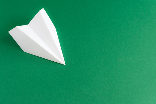 white paper plane on a green background